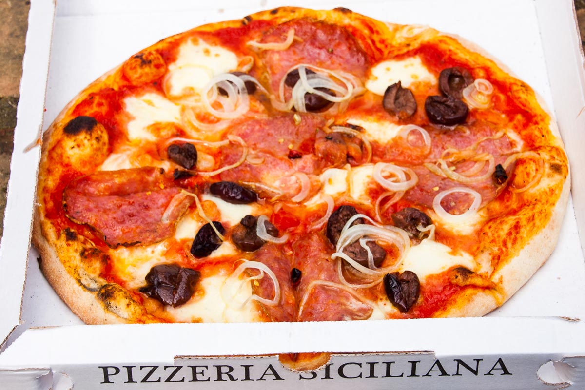 Pizza "Etna" con pomodoro, mozzarella, peperoncino, olive nere, salame piccante, cipolla